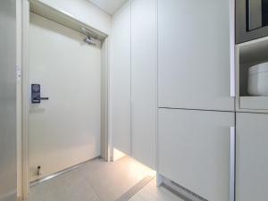 a white kitchen with a door and a microwave at Jeju Centerpoint N Residence in Jeju