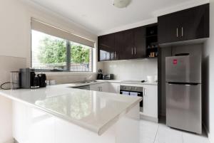 eine Küche mit einer weißen Arbeitsplatte und einem Kühlschrank in der Unterkunft Comfortable Home 10 Minutes from Town - Wifi and Garage in Newnham