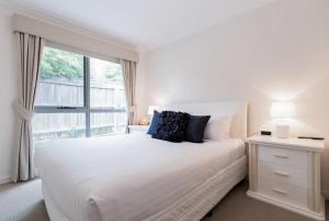 een witte slaapkamer met een groot bed en een raam bij Comfortable Home 10 Minutes from Town - Wifi and Garage in Newnham