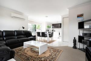 een woonkamer met een zwarte bank en een tafel bij Comfortable Home 10 Minutes from Town - Wifi and Garage in Newnham