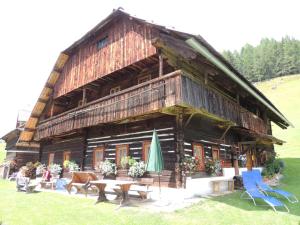 ein großes Holzgebäude mit Tischen und Stühlen davor in der Unterkunft Schrunerhof in Ebene Reichenau