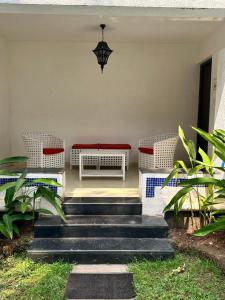 a porch with a bench and two wicker chairs at Riviera Hermitage in Anjuna