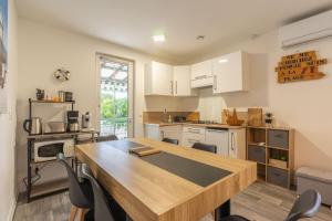 eine Küche mit weißen Schränken und einem Holztisch in der Unterkunft Maison de vacances centre ville in Ronce-les-Bains