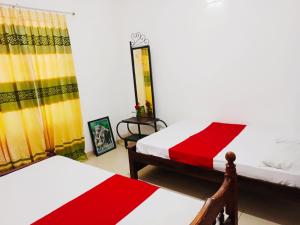 1 dormitorio con 2 camas con sábanas rojas y blancas en Blue louts, en Polonnaruwa