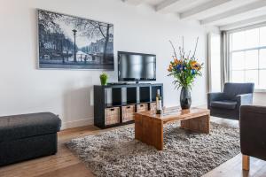 - un salon avec une télévision, un canapé et une table dans l'établissement Amsterdam Centre Harbour Apartments, à Amsterdam