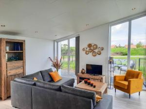 sala de estar con sofá, mesa y TV en Modern, high-quality chalet with WiFi, en Wemeldinge