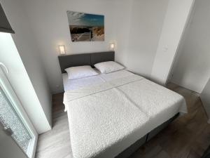 1 dormitorio pequeño con 1 cama con sábanas blancas en Modern, high-quality chalet with WiFi, en Wemeldinge