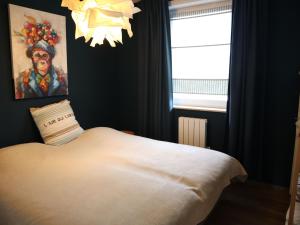 Schlafzimmer mit einem Bett mit einem Gemälde und einem Kronleuchter in der Unterkunft Apartment in Nieuwpoort with balcony in Nieuwpoort