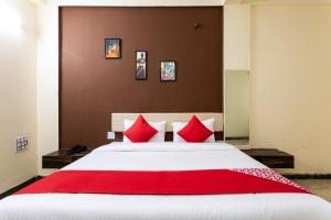 a bedroom with a large bed with red pillows at Hotel Santushti in Dewās