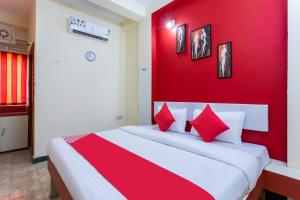 a bedroom with a red wall and a bed with red pillows at Hotel Santushti in Dewās