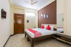 a bedroom with a large bed with red pillows at Hotel Santushti in Dewās