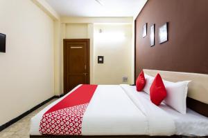 a bedroom with a large bed with red pillows at Hotel Santushti in Dewās