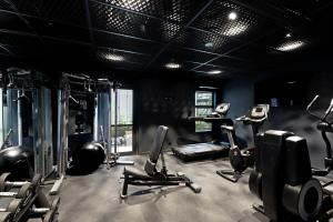 a gym with several treadmills and exercise bikes in a room at Abstract Hotel & Residences in Auckland