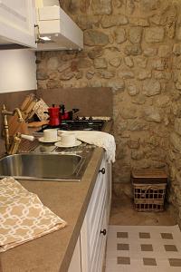 una cucina con lavandino e parete in pietra di Albergo Diffuso Polcenigo Ca' Bianca a Polcenigo