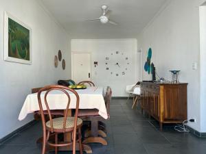 uma sala de jantar com mesa e cadeiras e um relógio na parede em apartamento fofo Astúrias no Guarujá