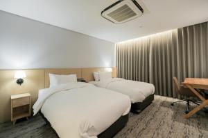 a hotel room with two beds and a desk at Aank Hotel Incheon Guwol in Incheon