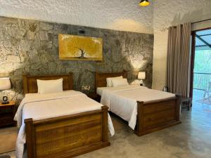 een slaapkamer met 2 bedden en een stenen muur bij Arsulana Eco Lodge & Spa in Ginigathena