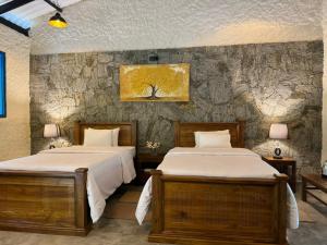 two beds in a room with a stone wall at Arsulana Eco Lodge & Spa in Ginigathena