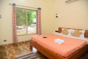 1 dormitorio con cama con sábanas de color naranja y ventana en ZIRAD 7BHK VILLA ALIBAUG WITH GAZEBO & POOL, en Alibaug