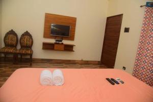 1 dormitorio con 1 cama con zapatillas blancas y TV en ZIRAD 7BHK VILLA ALIBAUG WITH GAZEBO & POOL, en Alibaug