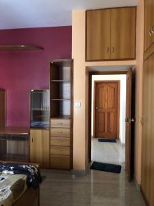a room with a bed and a kitchen with a door at Mahagiri Nest in Mysore