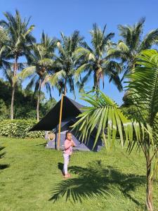 a young child standing in front of a tent with palm trees at Campo Duro Ecolodge in Puerto Villamil