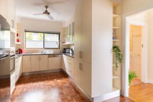 a kitchen with white cabinets and a ceiling fan at Birkinshaw Villa ( 3 Bedroom with Parkings ) in Broadview