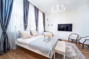 a white bedroom with a bed and a chandelier at Best Point in the City / 2 Bedrooms in Sofia