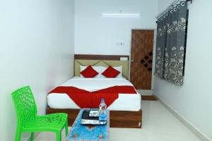 a bedroom with a bed and a green chair at CHANDRODAYAM RESIDENCY in Karaikal