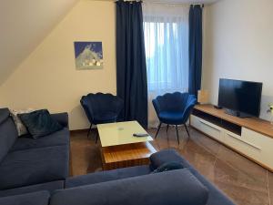 salon z kanapą, krzesłami i telewizorem w obiekcie Apartamenty Prima w Dziwnówku