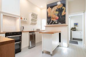 una cocina blanca con una pintura en la pared en Charming On Charles, en Launceston