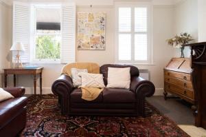 a living room with a brown couch and a dresser at Charming On Charles in Launceston