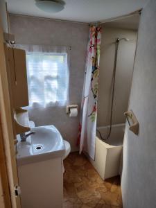 a small bathroom with a sink and a shower at Domki holenderskie HEL in Hel