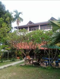 un edificio con un tavolo da picnic e alberi di fronte ad esso di Thakhek Travel Lodge a Thakhek
