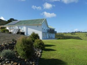 un edificio blanco con techo verde en un campo en The Healthy Guesthouse 