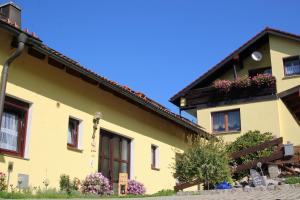 une maison jaune avec des fleurs dans les fenêtres dans l'établissement Ferienwohnung Werner, à Warmensteinach