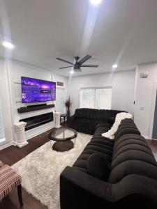 a living room with a black couch and a flat screen tv at The Getaway House ATL in Carrollton