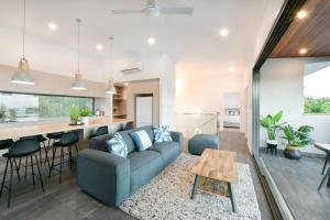 ein Wohnzimmer und eine Küche mit einer Couch und einem Tisch in der Unterkunft Elementa Whitsundays in Airlie Beach