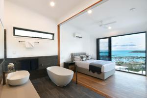 ein Schlafzimmer mit Bett und Blick auf das Meer in der Unterkunft Elementa Whitsundays in Airlie Beach