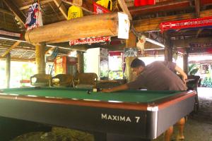 un homme jouant au billard dans l'établissement Driftwood Village Resort, à Sipalay