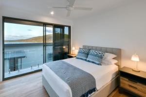 ein Schlafzimmer mit einem Bett und einem großen Fenster in der Unterkunft Elementa Whitsundays in Airlie Beach