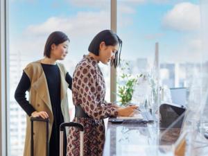zwei Frauen, die in einem Büro stehen und einen Laptop ansehen in der Unterkunft Hotel Resol Trinity Hakata in Fukuoka