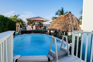 uma piscina com uma cadeira e um guarda-sol de palha em Hammock Haven em Key Largo