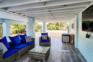 un porche cubierto con sofás azules y una mesa en Hammock Haven en Cayo Largo