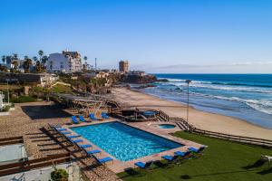 a swimming pool next to a beach with chairs and the ocean at Casa Marfil 26 - Playa Arcangel in Rosarito