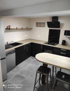 uma cozinha com armários pretos e uma mesa de madeira em L'escapade em Julos