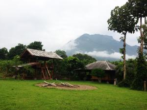 a house in a field with a mountain in the background at Yang Tone Farm Stay in Chiang Dao