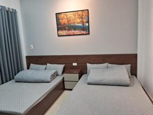 a bedroom with two beds and a painting on the wall at Villa GinnHouse Mộc Châu 1 in Mộc Châu