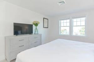 a white bedroom with a television and a white dresser at Harbourtown Suites, Unit 211 in Plymouth