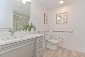 a white bathroom with a toilet and a sink at Harbourtown Suites, Unit 211 in Plymouth